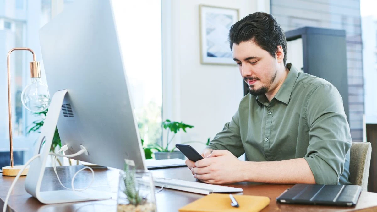 Rep in a green shirt reading his phone at his desk before a call