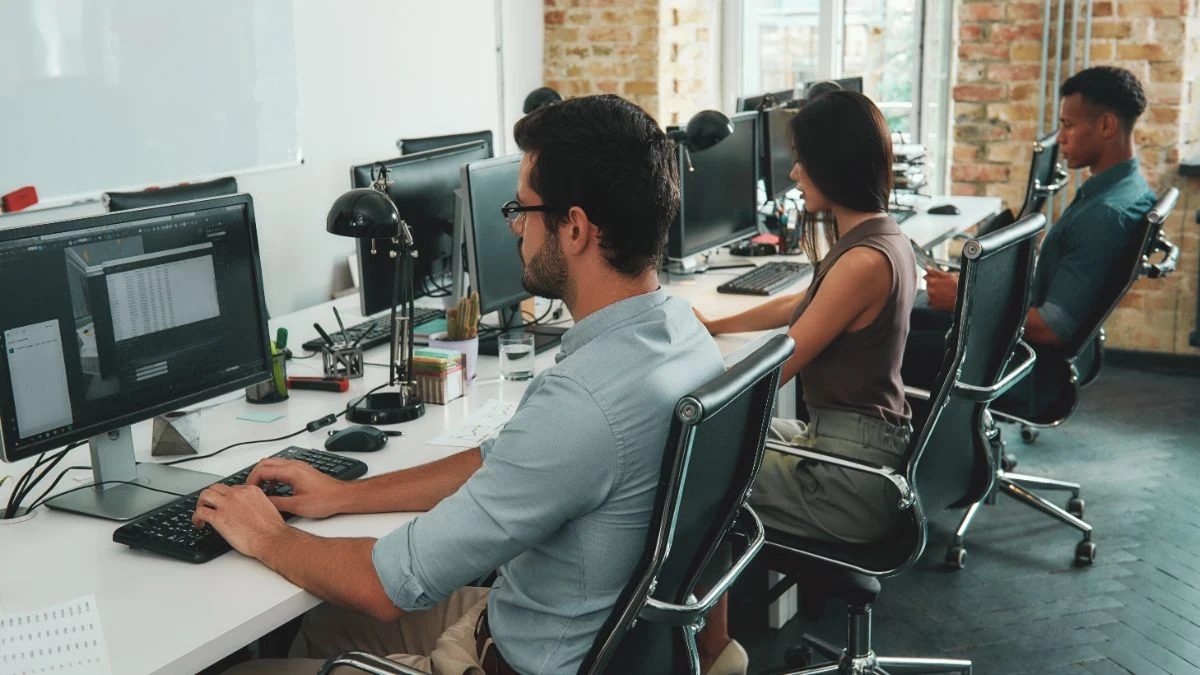 SaaS sales team working side by side at a row of desks in a modern office