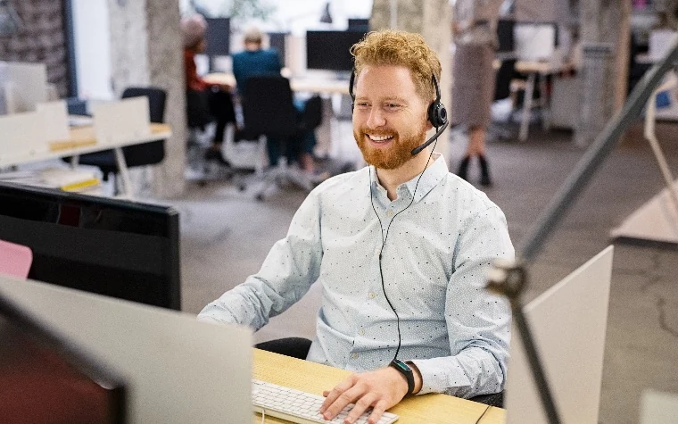 Sales manager coaching at a computer in an open office