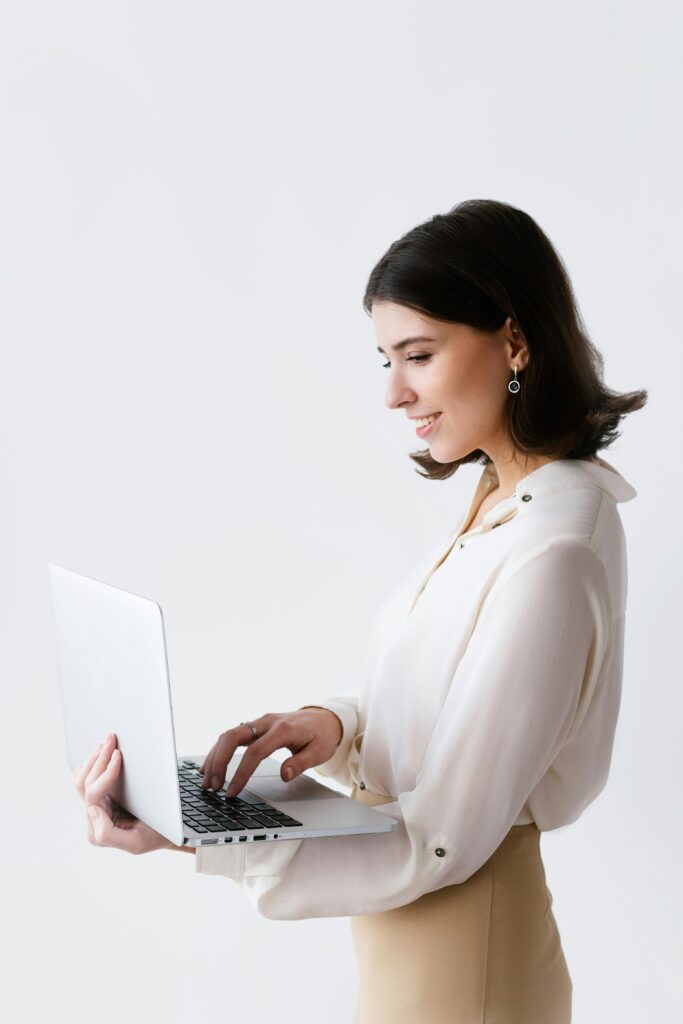 Side view of a businesswoman typing on a laptop against a white background in a studio.