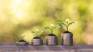 Four stacks of coins with small plants growing from the top, representing growth and investment.